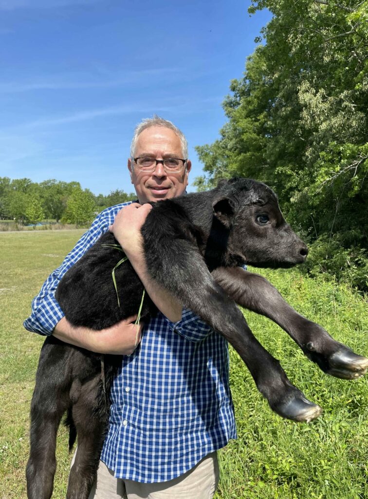 Join Our herd image of Robert holding newborn Angus calf