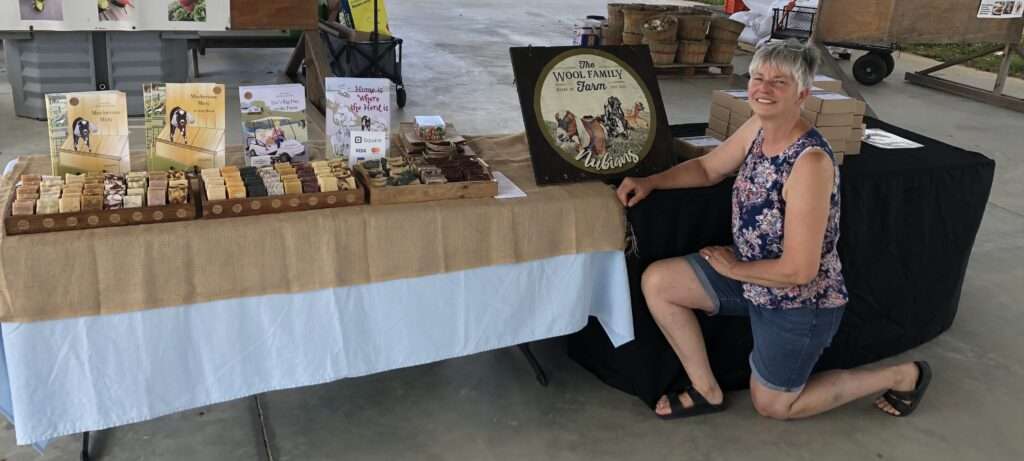 Artisan soapmaker Evelyn Wool poses with soap boxes, soap and children's books